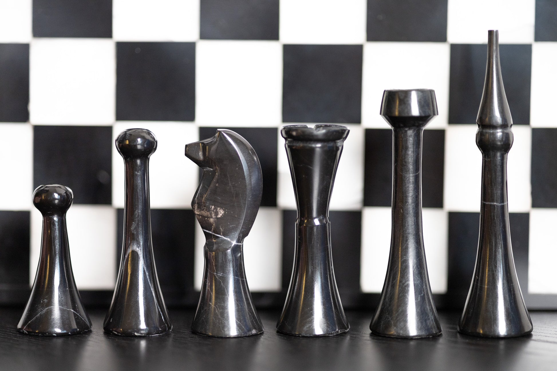 Detailreiche Nahaufnahme der schwarzen Marmor-Schachfiguren von Marmonix, die vor dem Brett aufgereiht sind, um die unterschiedlichen Größen und die präzise handgefertigte Qualität jeder einzelnen Spielfigur perfekt zu zeigen.
