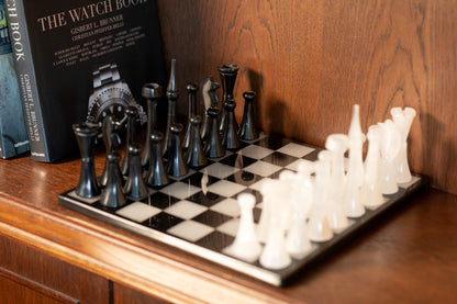 Das luxuriöse Schachspiel aus Onyx und Marmor von Marmonix, stilvoll platziert in einem edlen Bücherregal neben ausgewählten Büchern als anspruchsvolles, skulpturales Deko-Objekt für den Wohnbereich.