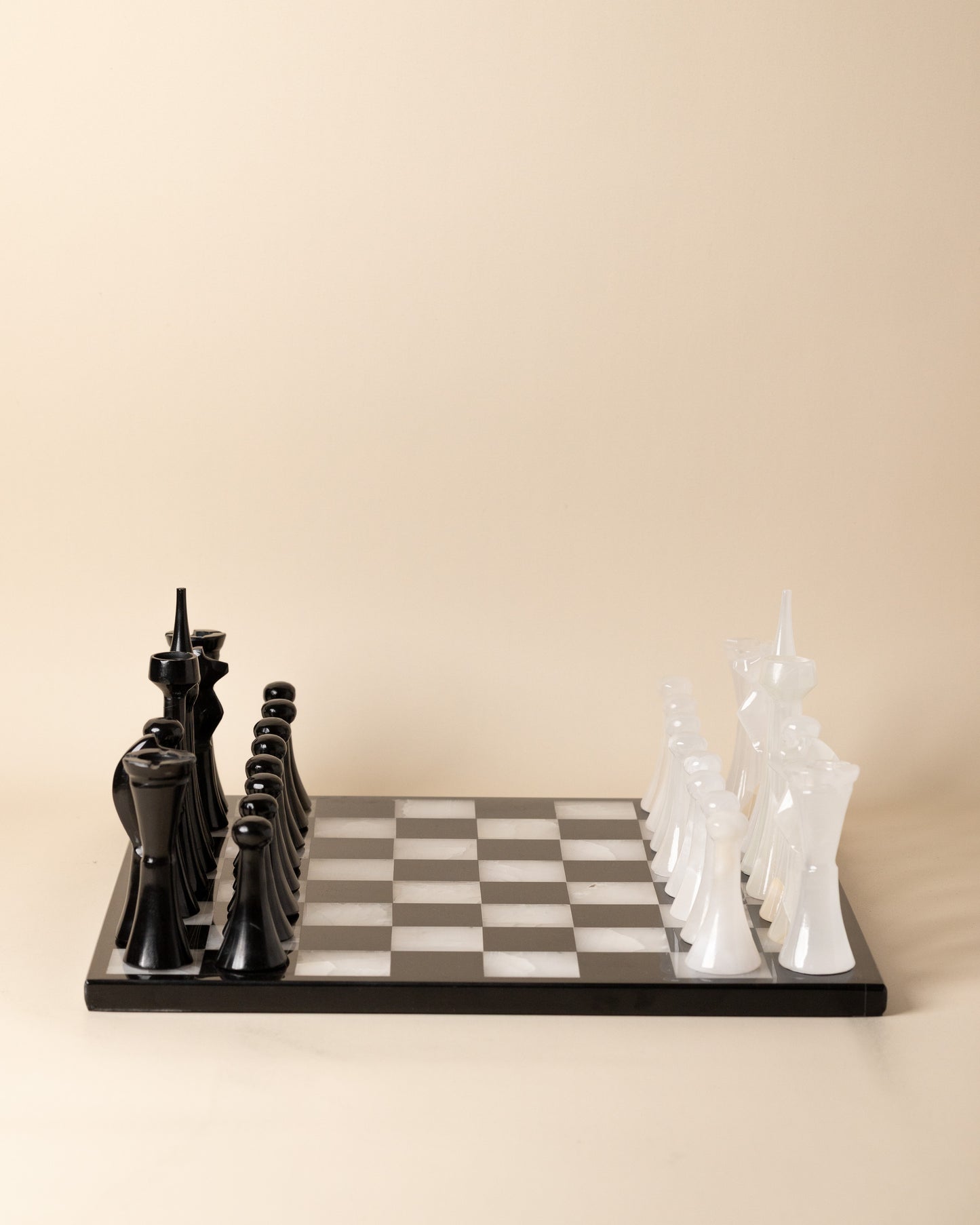 Chessboard with black and white chess pieces on a beige background