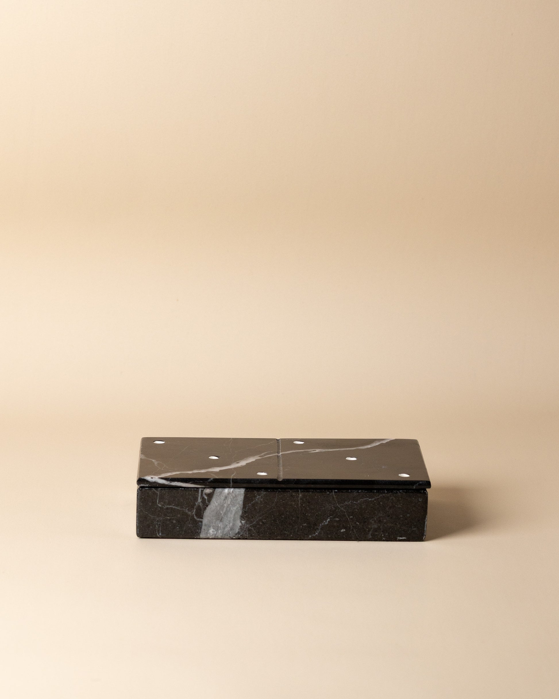 Black marble domino set on a beige background