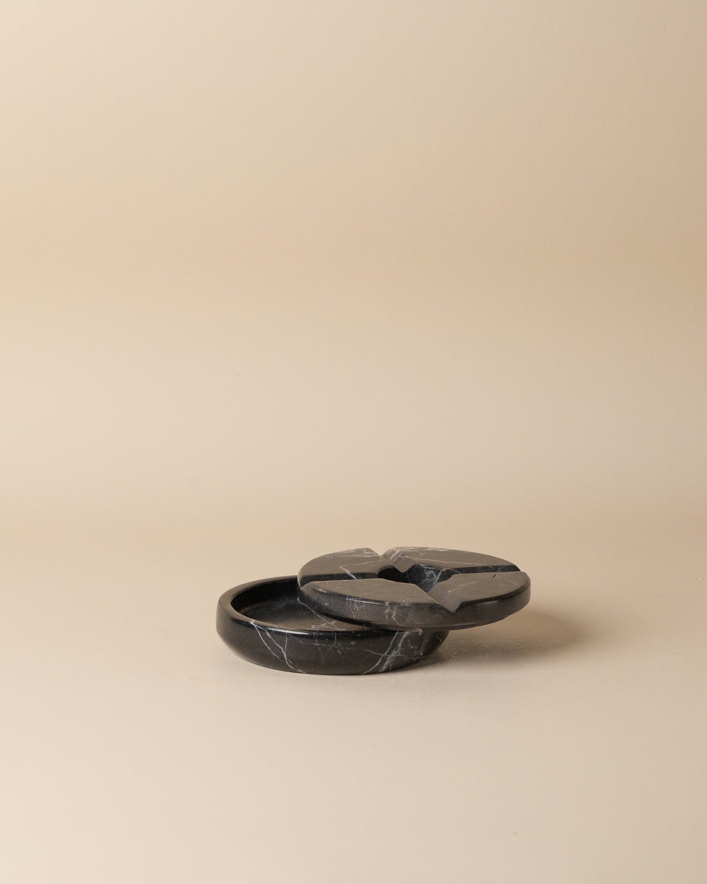 Lidded black stone ashtray on a beige background