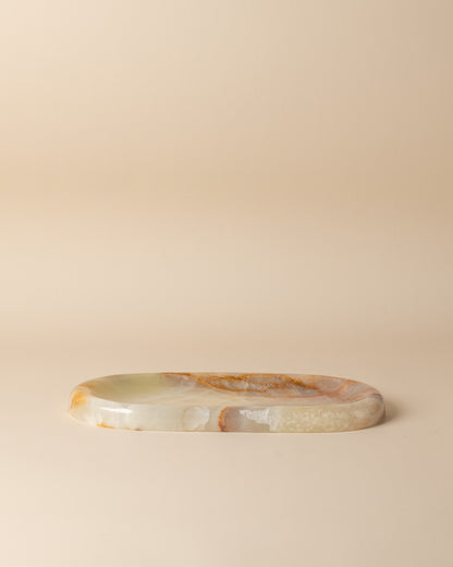 Oval stone tray with onyx translucent green and brown patterns on a beige background