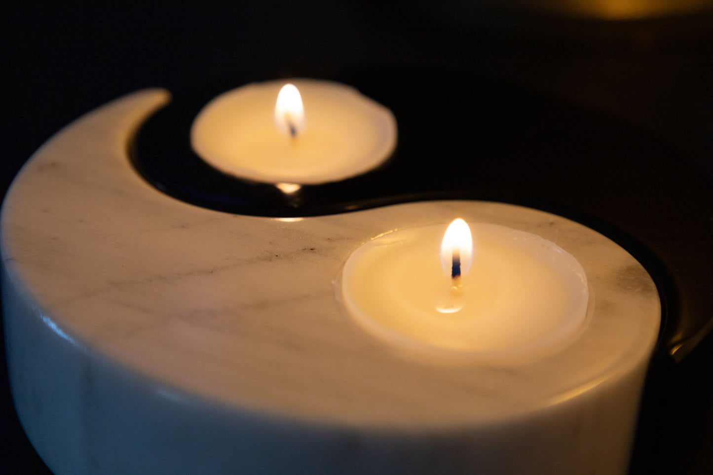 Harmonisches Ambient-Bild des Yin-Yang-Teelichthalters aus schwarzem und weißem Marmor von Marmonix, das beruhigendes Kerzenlicht ausstrahlt.